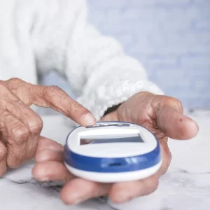Idosa com diabetes verificando os níveis de glicose no sangue com um medidor digital.