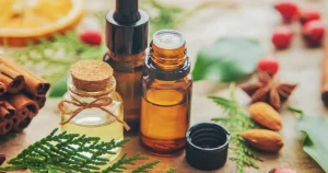 Frascos de óleos essenciais naturais com canela, anis e folhas verdes, utilizados em terapias como aromaterapia e cuidados integrativos