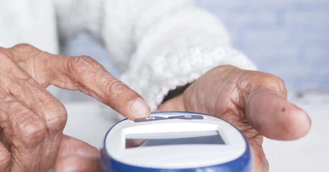 Idosa com diabetes verificando os níveis de glicose no sangue com um medidor digital.